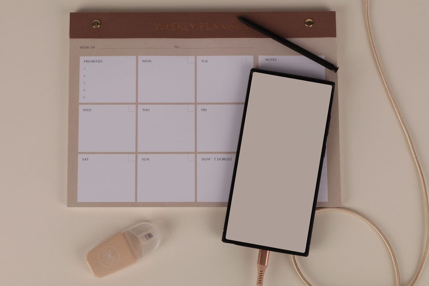 A weekly planner pad with a smartphone and a pen resting on it